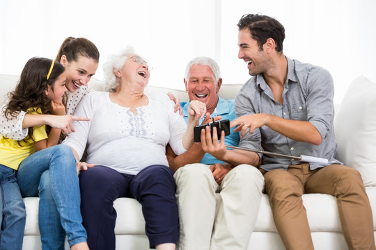 一家人看着智能手机上的照片大笑