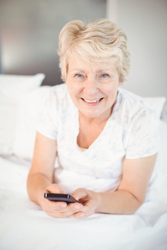 坐在床上使用手机的老太太