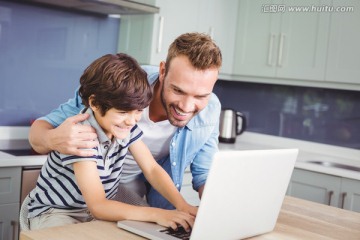 微笑的父亲和儿子在用笔记本电脑