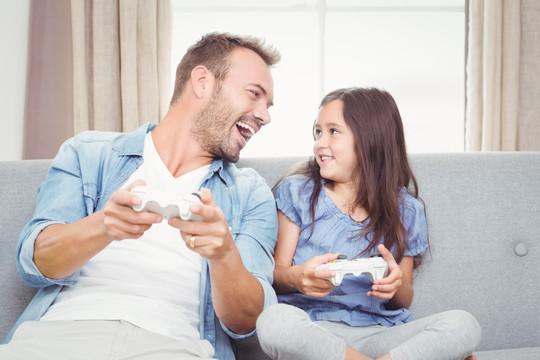 微笑的父亲和女儿玩电子游戏