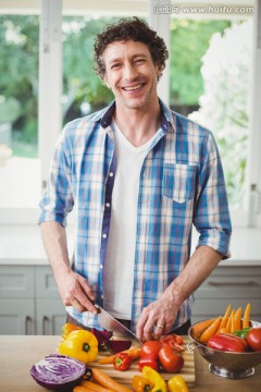 微笑的男人在厨房里切蔬菜