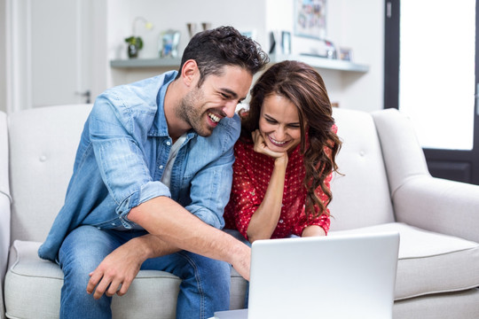 微笑的夫妇在使用笔记本电脑