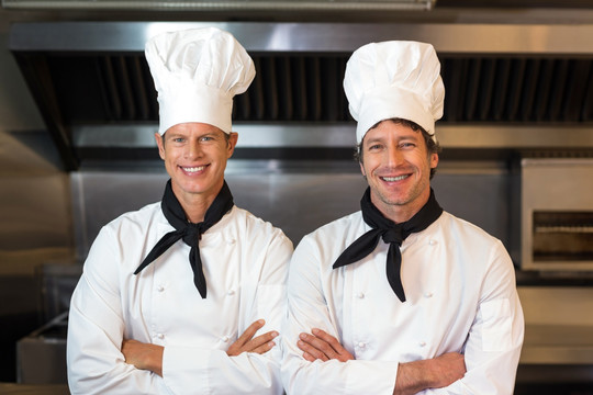 抱着双臂站在厨房里的两名男厨师