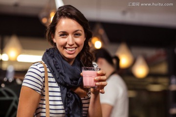 微笑的女人在咖啡馆里喝奶昔