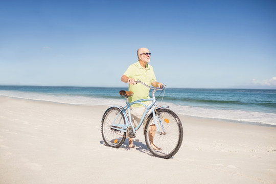 拖着自行车走在沙滩上的老人
