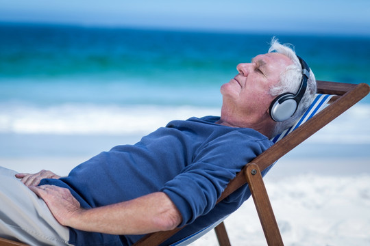 躺在沙滩椅上听歌的男人