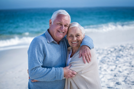 在沙滩上彼此拥抱的老夫妇