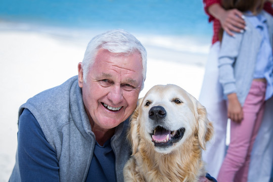 微笑的老人和狗狗在沙滩上