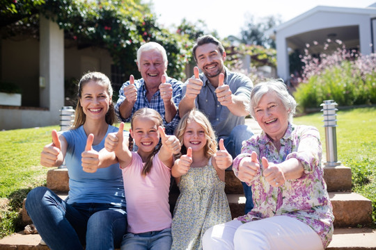 微笑的家人坐在后院里竖起大拇指