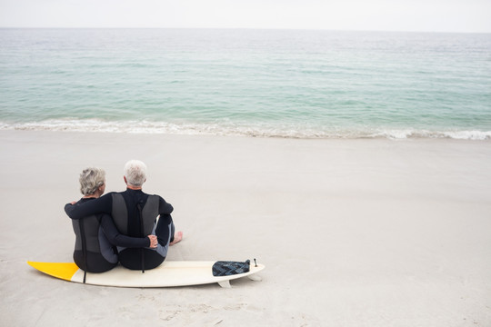 坐在冲浪板上看着大海的老夫妇