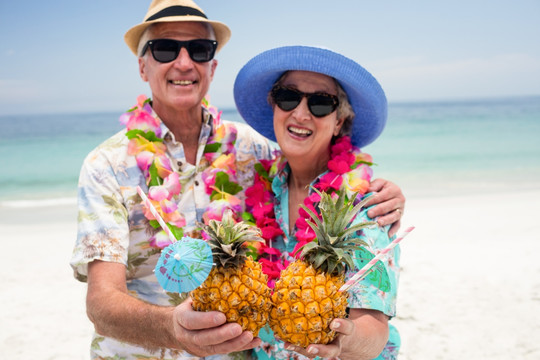 在海边拿着菠萝饮料的夫妇