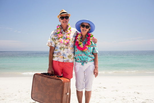 老夫妇拿着手提箱在海滩上