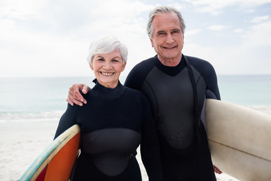 拿着冲浪板站在海边的老夫妇