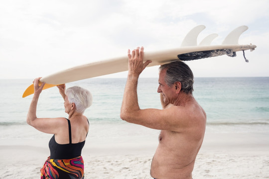 举着冲浪板放在头上的老年夫妇