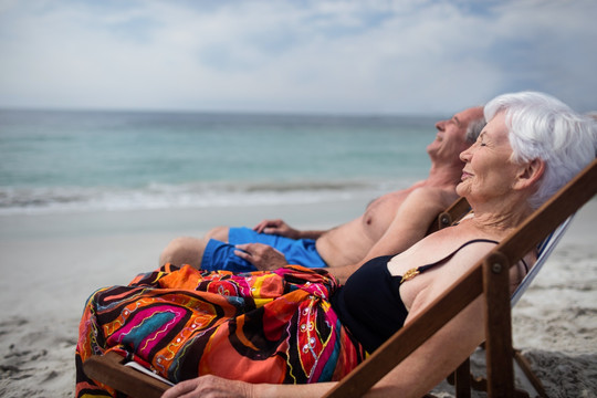 躺在沙滩椅上看着大海的老夫妇