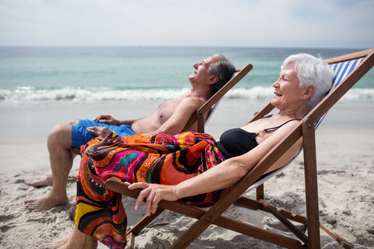 幸福的老夫妇躺在沙滩椅上