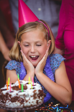 惊讶的女孩看着生日蛋糕