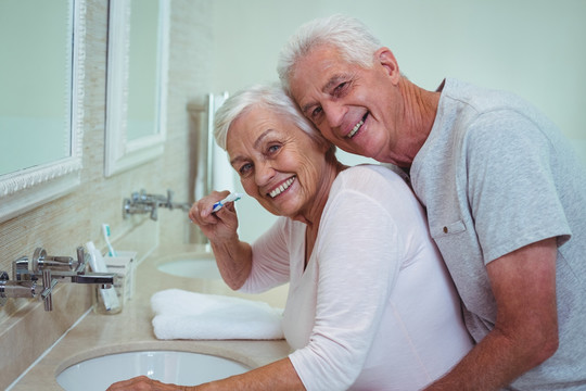 男人在浴室里拥抱刷牙的妻子
