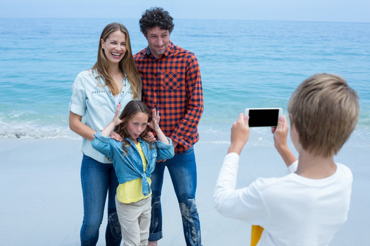 在海边给家人拍照的男孩