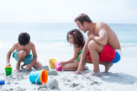 在沙滩上陪孩子玩沙子的父亲