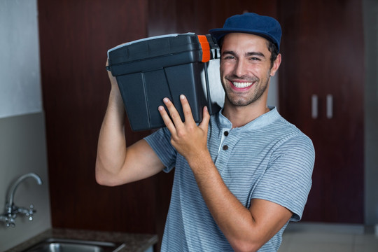 微笑的男工人扛着工具箱