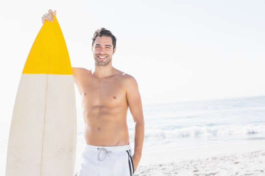 男子拿着冲浪板在沙滩上
