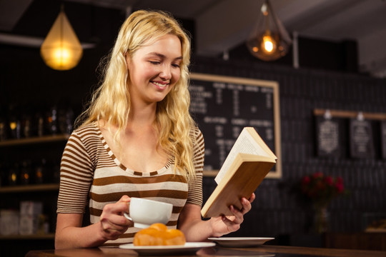 微笑的女人在咖啡馆里看书