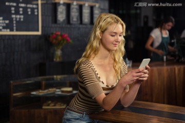 在咖啡馆里使用手机的金发女人