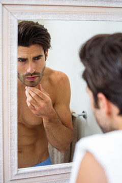 在浴室里检查下巴胡子的男人