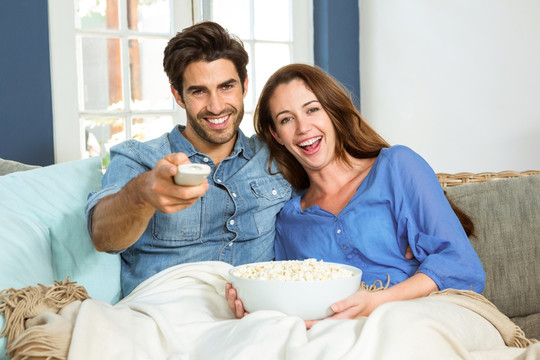 年轻夫妇在看电视时吃爆米花