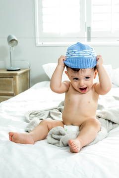 可爱的小男孩坐在床上戴着帽子