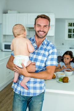 微笑的男人抱着孩子在厨房里