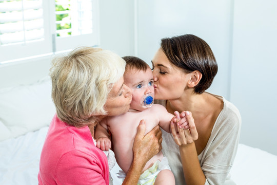 亲吻婴儿的祖母和母亲
