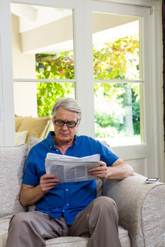在家里阅读报纸的老人