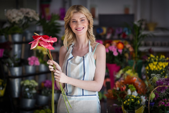 微笑的女人在花店里拿着花束