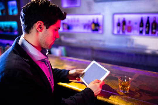 在酒吧使用平板电脑的男人