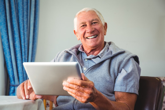 微笑着使用平板电脑的老年人