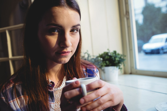 漂亮的年轻女人拿着一杯咖啡