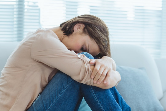 伤心的年轻女人坐在家里的沙发上