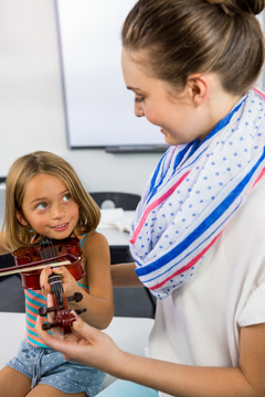 微笑的老师协助女孩拉小提琴