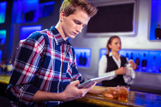 在酒吧使用平板电脑的商务男人