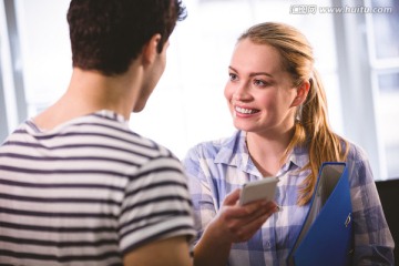 微笑着看着手机的商务男女