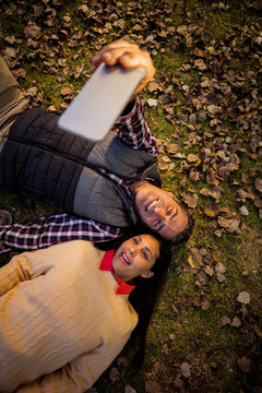 躺在草地上用手机自拍的夫妇