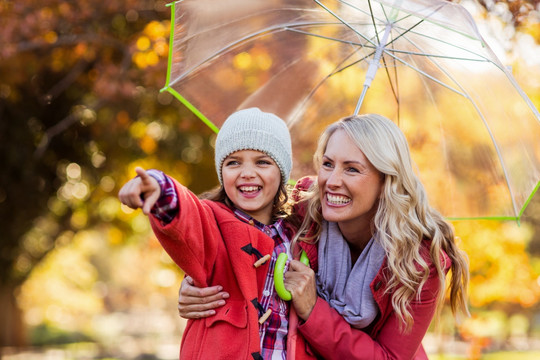 撑着雨伞的女人带着女儿在公园里