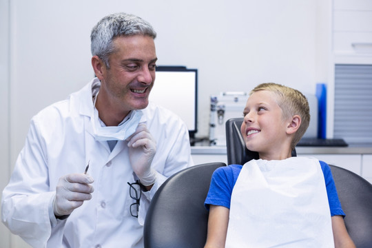 微笑的牙医与年轻的病人交谈