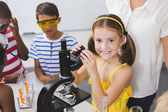 在实验室使用显微镜的小学生