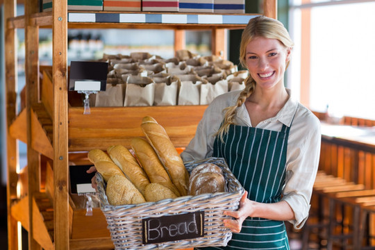 微笑的女员工拿着一篮面包