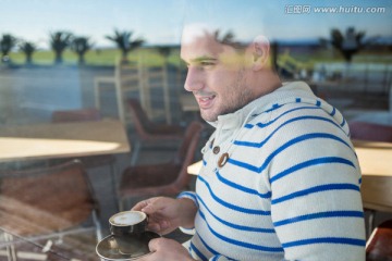 微笑的男人在咖啡馆里喝咖啡