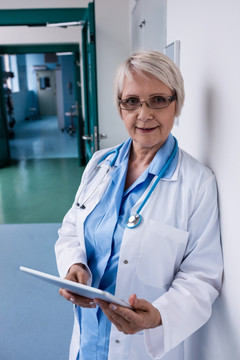 站在医院走廊用平板电脑的女医生