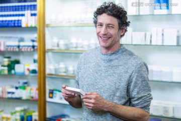 在药店里拿着一盒药的男顾客